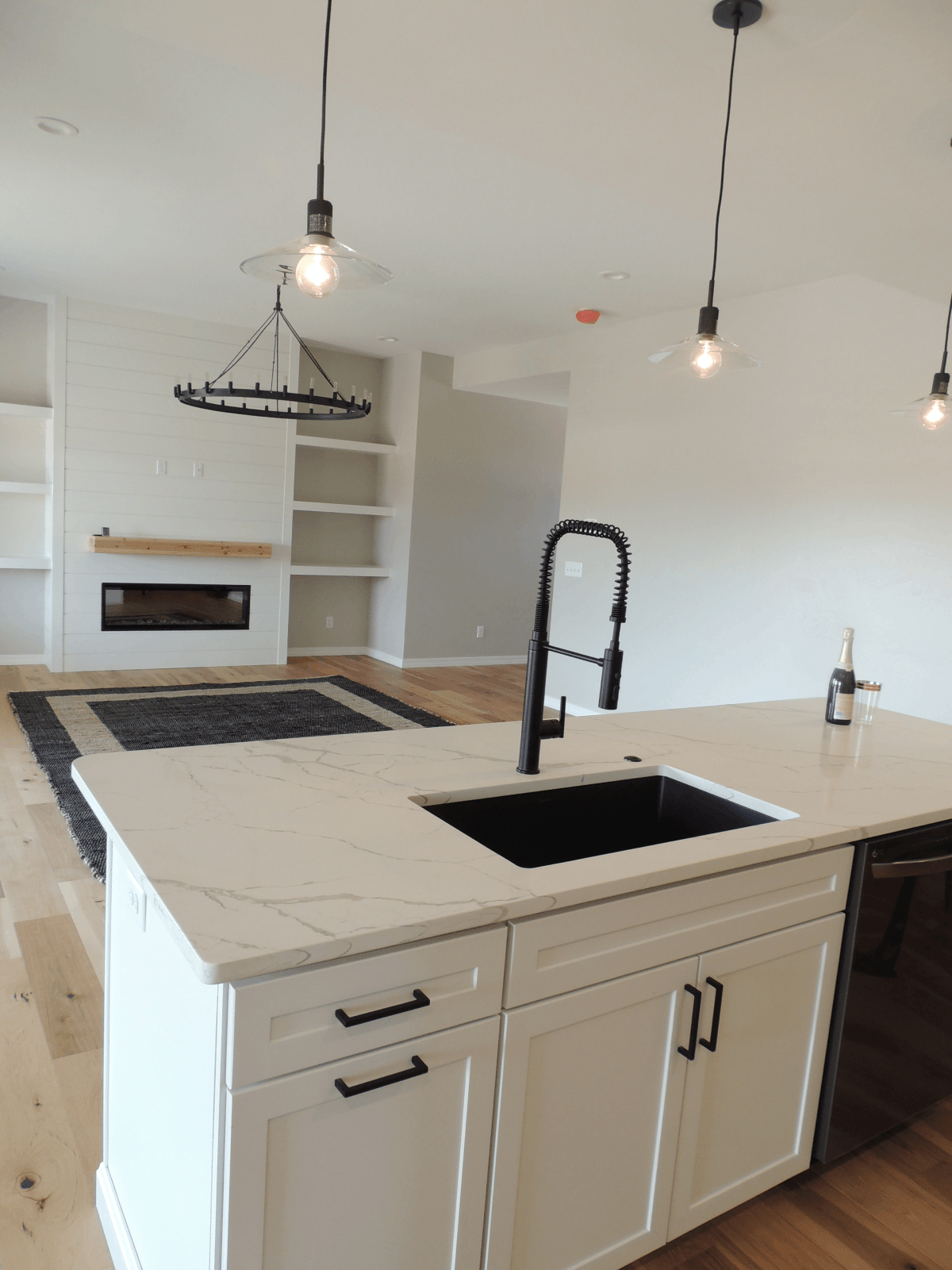 A kitchen with white cabinets , a sink , and a fireplace.