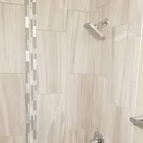 A shower with a shower head and a tiled wall.