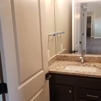 A bathroom with a sink , mirror and cabinets.
