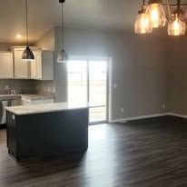 An empty kitchen with a large island and sliding glass doors.