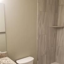 A bathroom with a toilet , sink , shower and mirror.