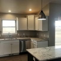 A kitchen with white cabinets , granite counter tops , a sink and a refrigerator.