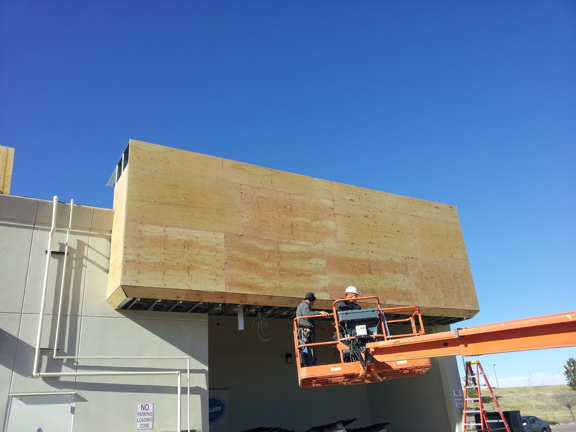 A man in a crane is working on the side of a building