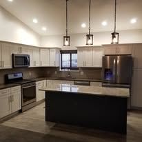A kitchen with stainless steel appliances , white cabinets , and a large island.