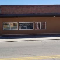 A brown building with a lot of windows is sitting on the side of the road.