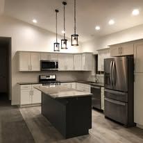 A kitchen with white cabinets , stainless steel appliances , and a large island.