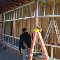 A man is standing next to a ladder in front of a building under construction.