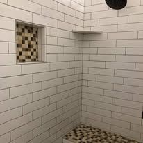 A shower with white brick walls and a tiled floor.