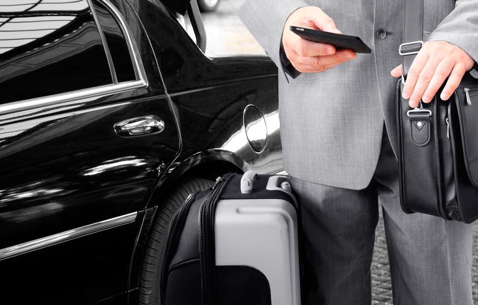 Un hombre con traje está de pie junto a una maleta y un maletín.