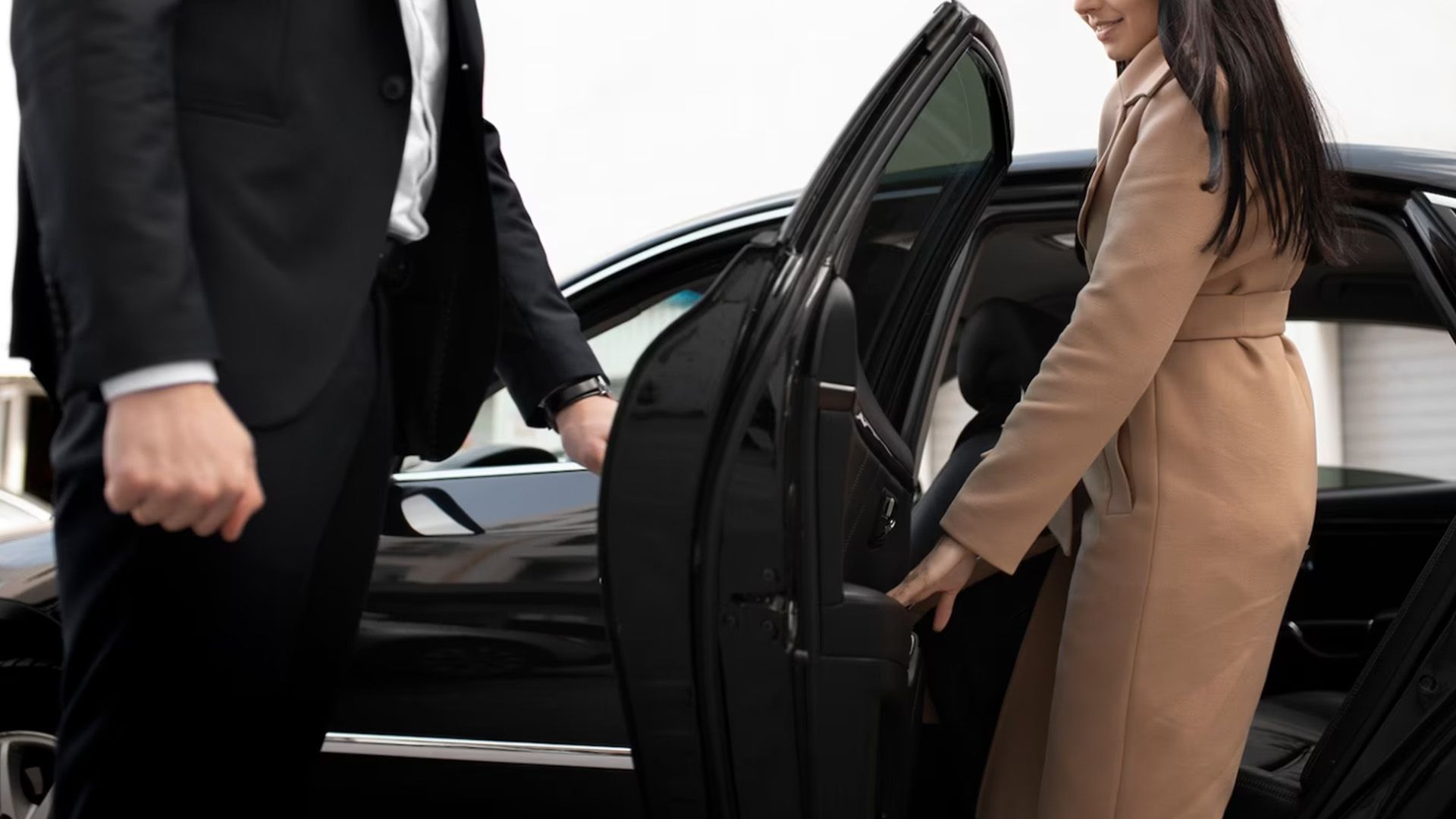 Un hombre con traje está ayudando a una mujer a salir de un coche.