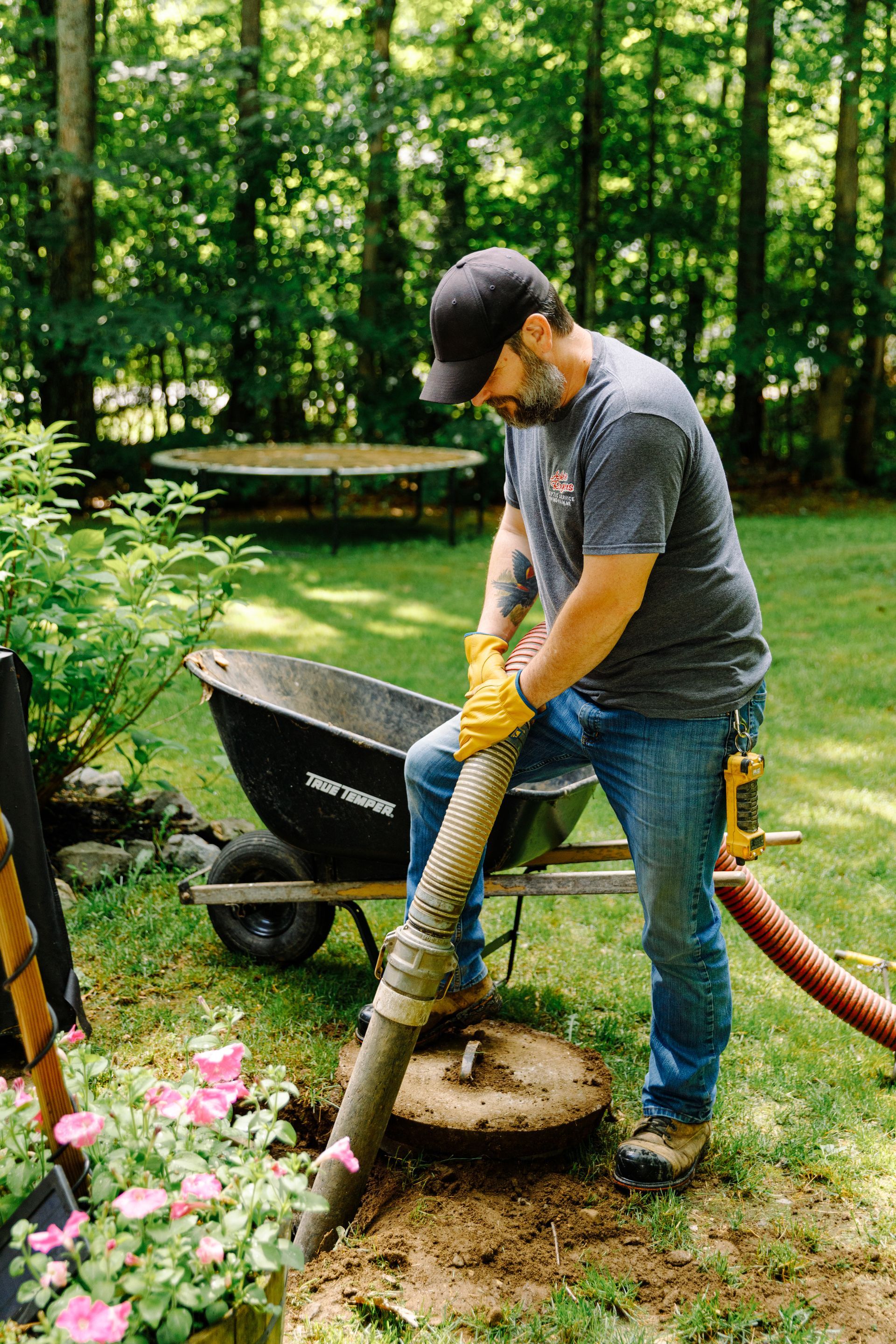 A man is using a vacuum hose to clean a septic tank.