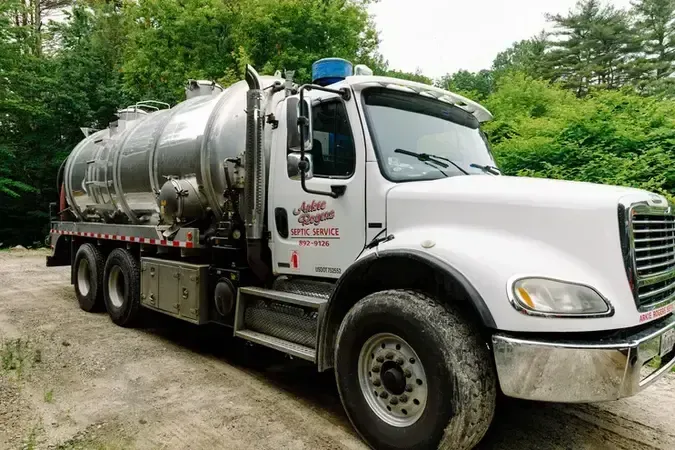 A large white Arkie Rogers truck is parked in a dirt lot.