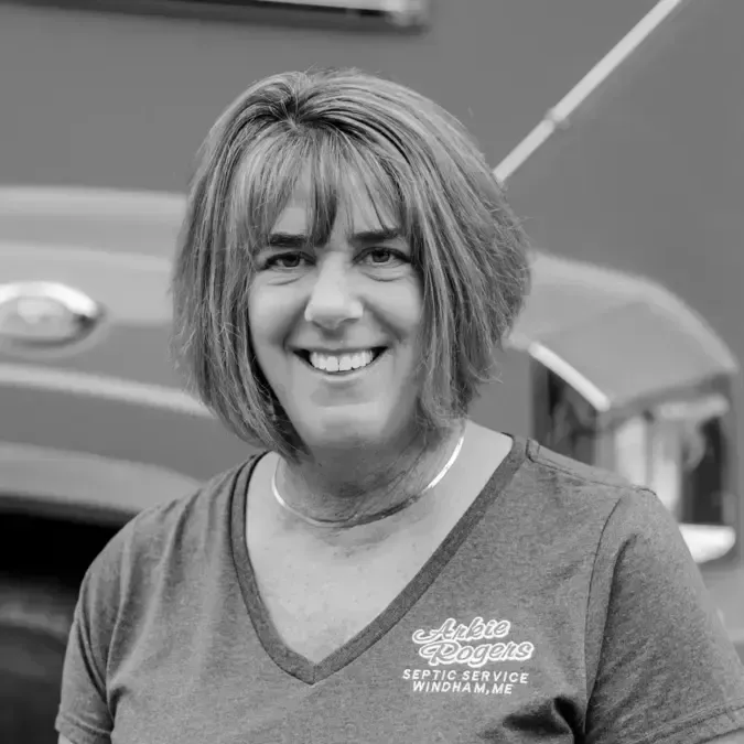 A woman is smiling in front of a truck in a black and white photo. Arkie Rogers Employee