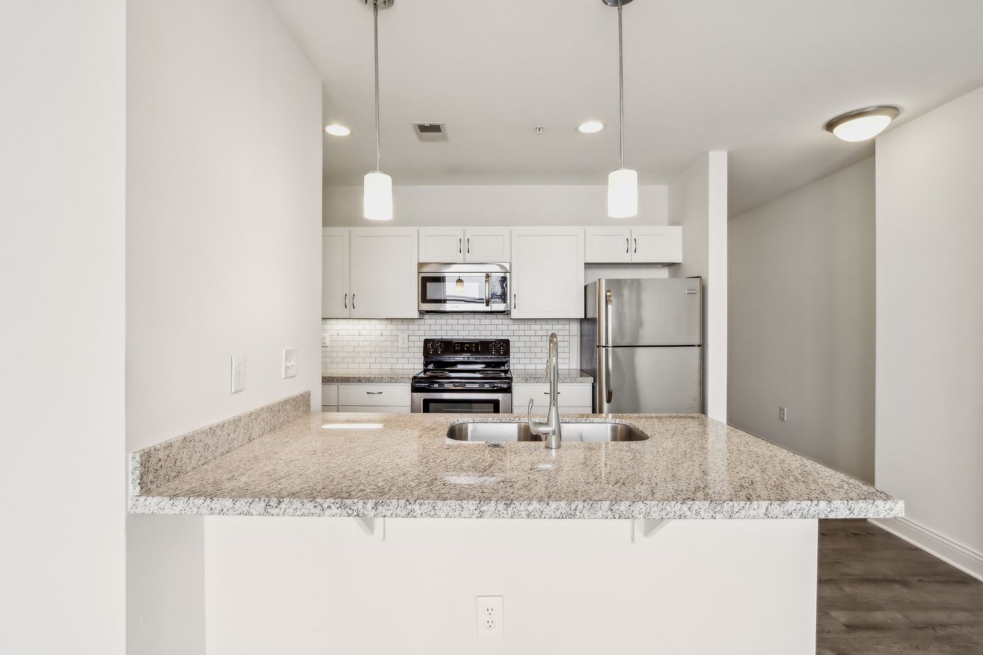 A kitchen with granite counter tops , stainless steel appliances , and white cabinets.