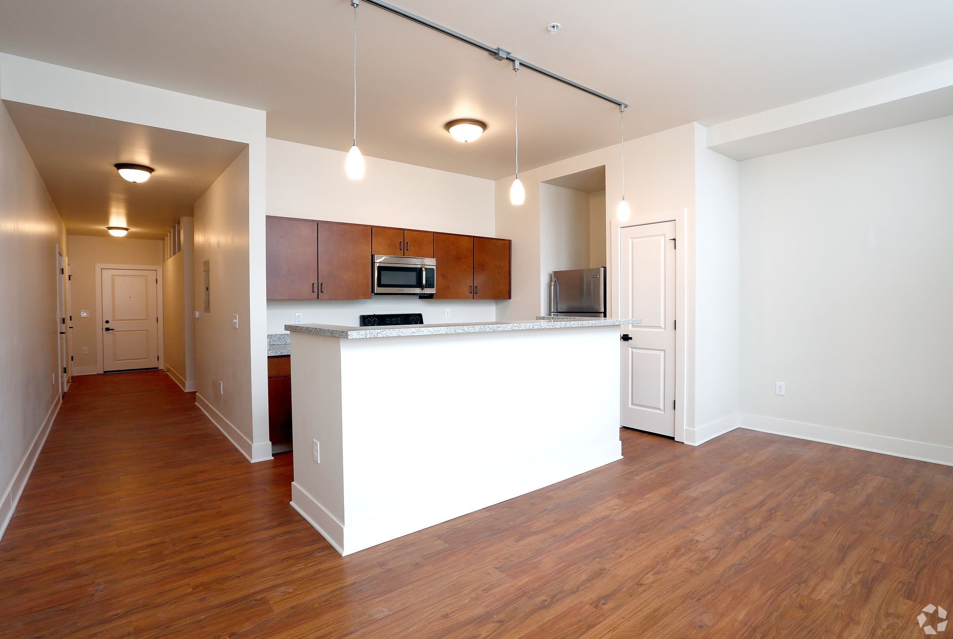 An empty apartment with hardwood floors and white walls