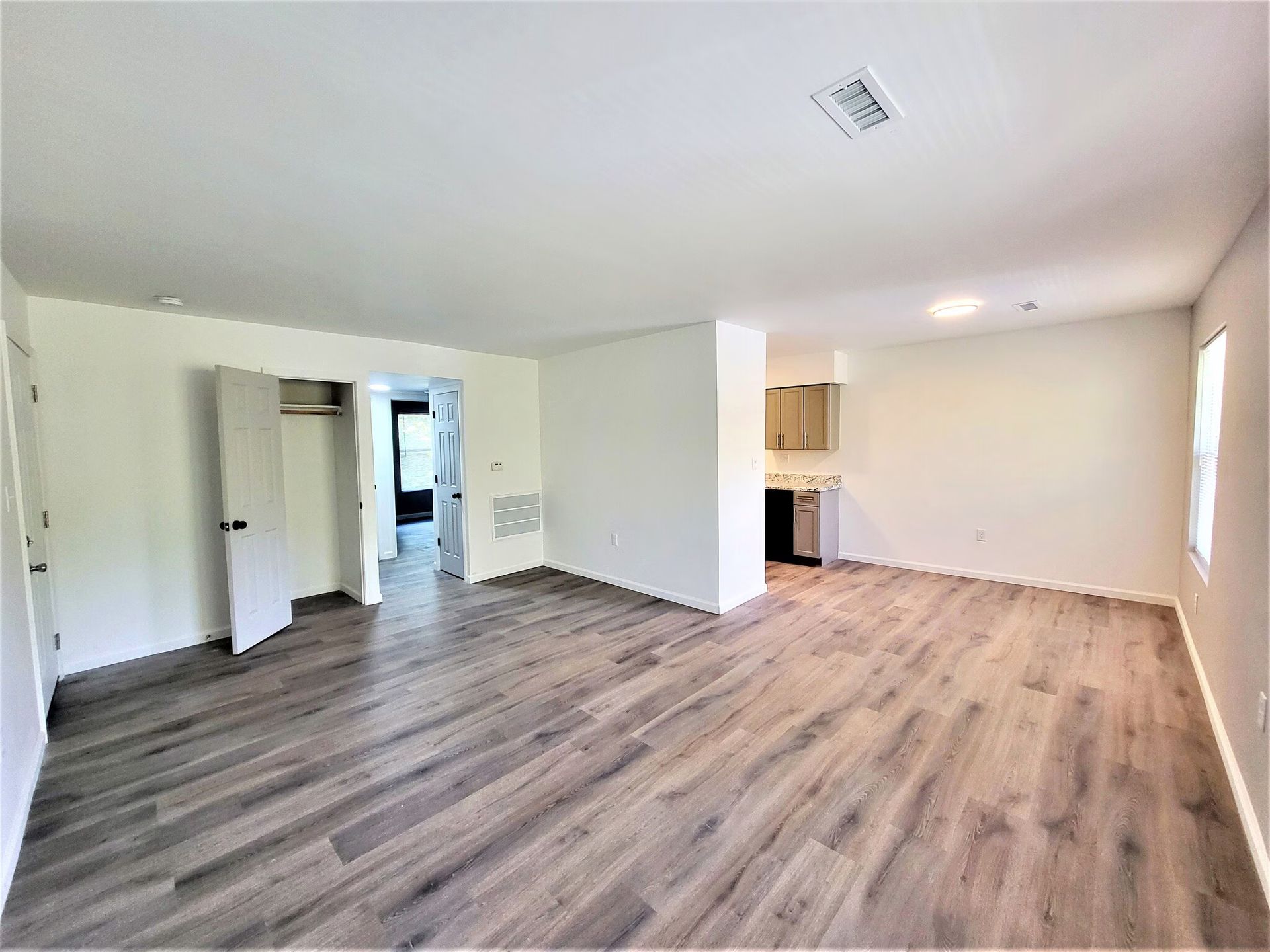 An empty living room with hardwood floors and white walls.