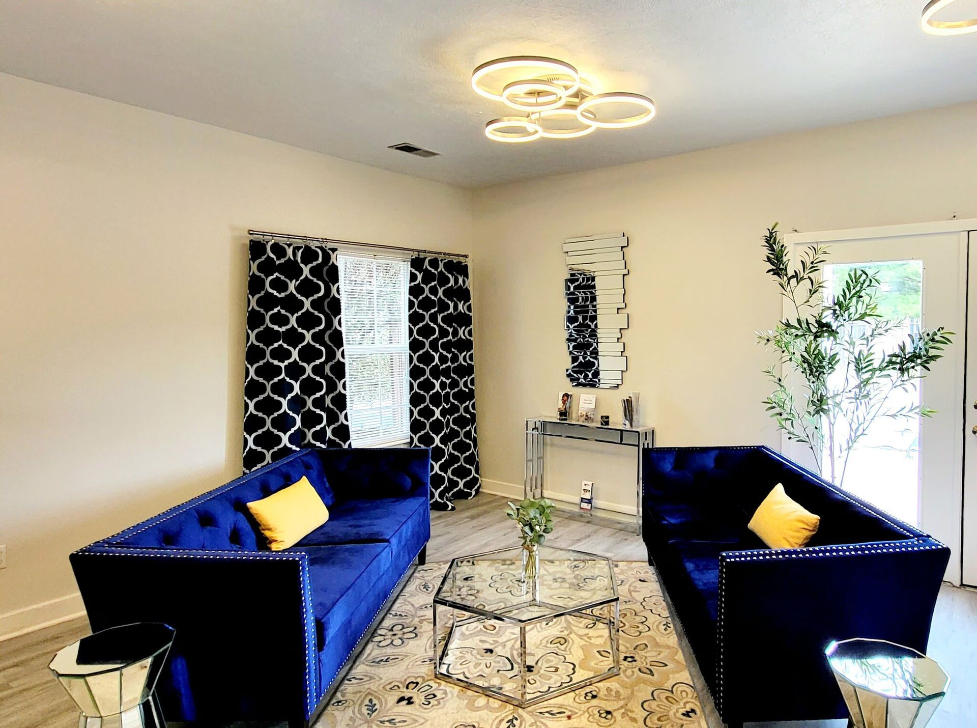 A living room with two blue couches and a glass coffee table.