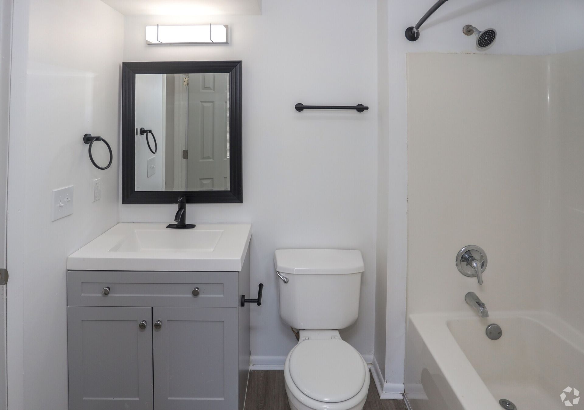 A bathroom with a toilet , sink , mirror and bathtub.