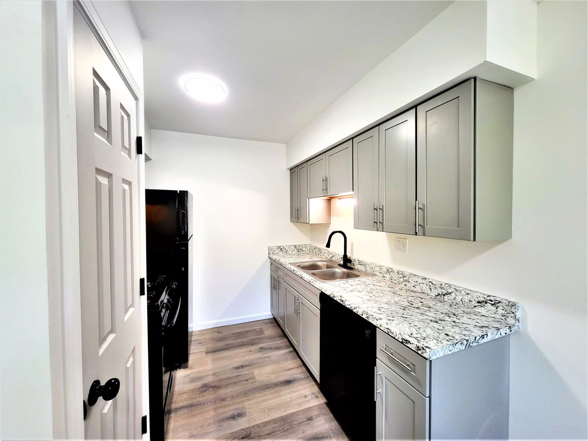 A kitchen with gray cabinets and granite counter tops.
