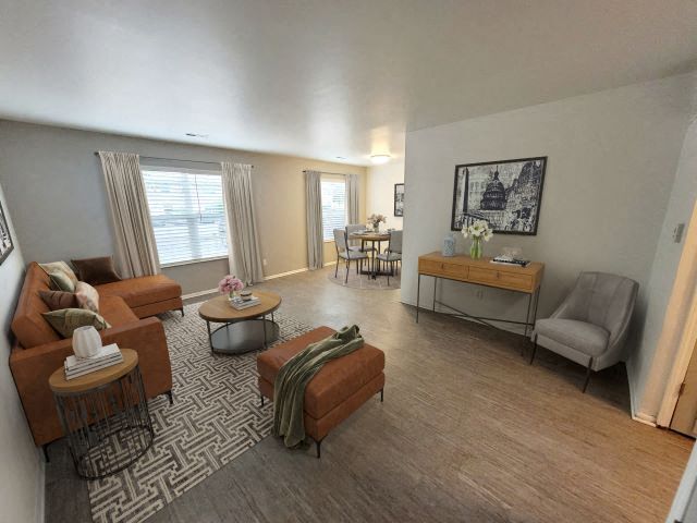 A living room with a couch , chair , coffee table and ottoman.