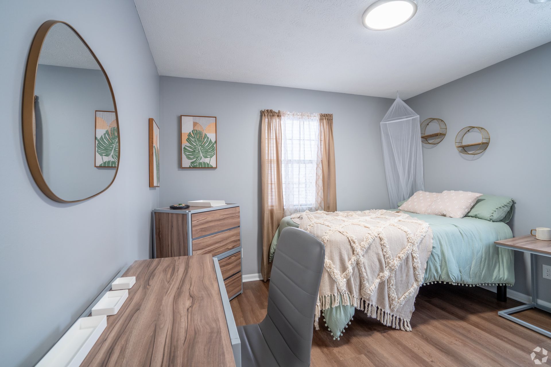 A bedroom with a bed , desk , dresser and mirror.