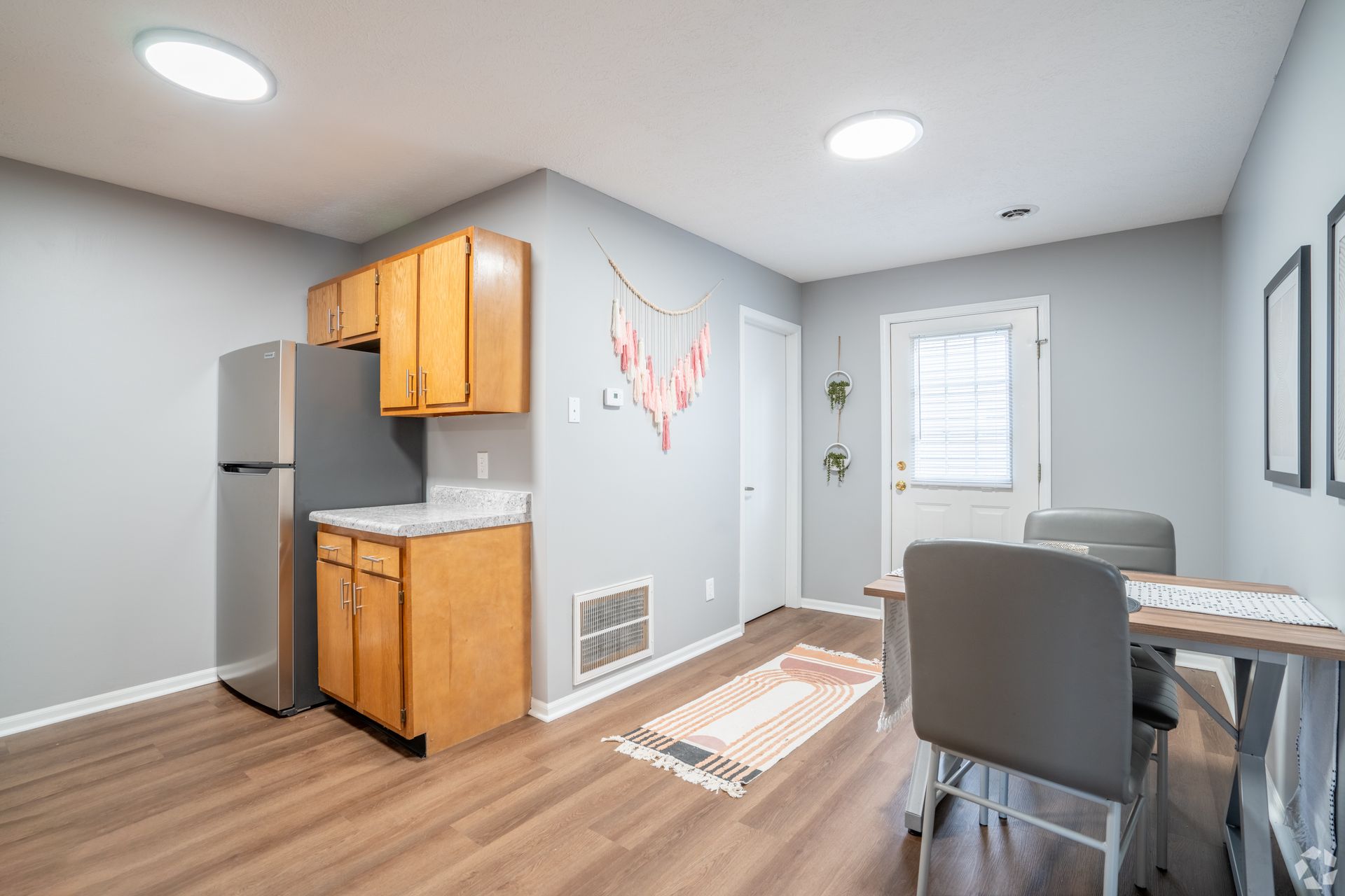 A kitchen with a refrigerator , sink , table and chairs.