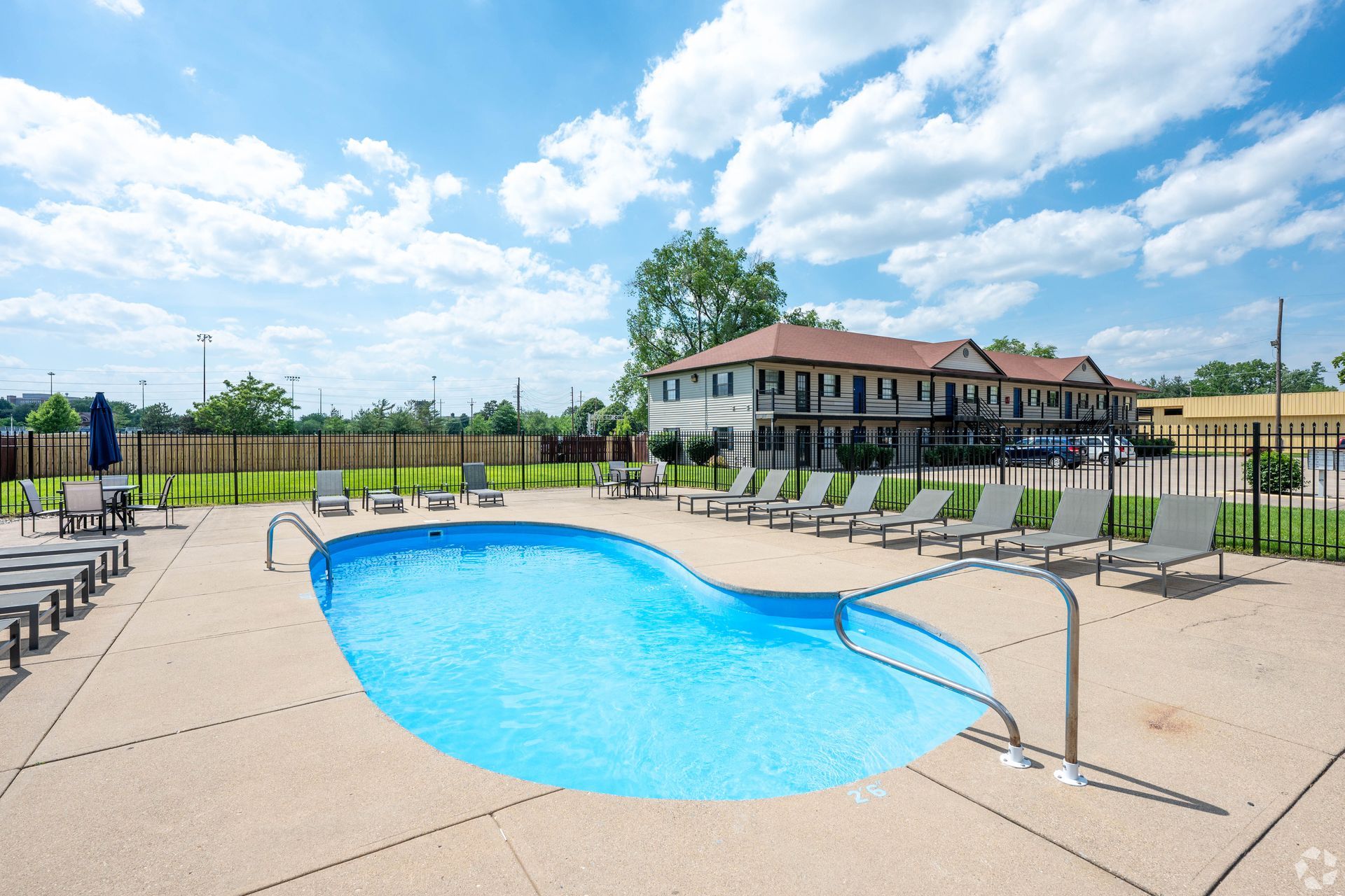 A large swimming pool surrounded by chairs and umbrellas in front of a building.