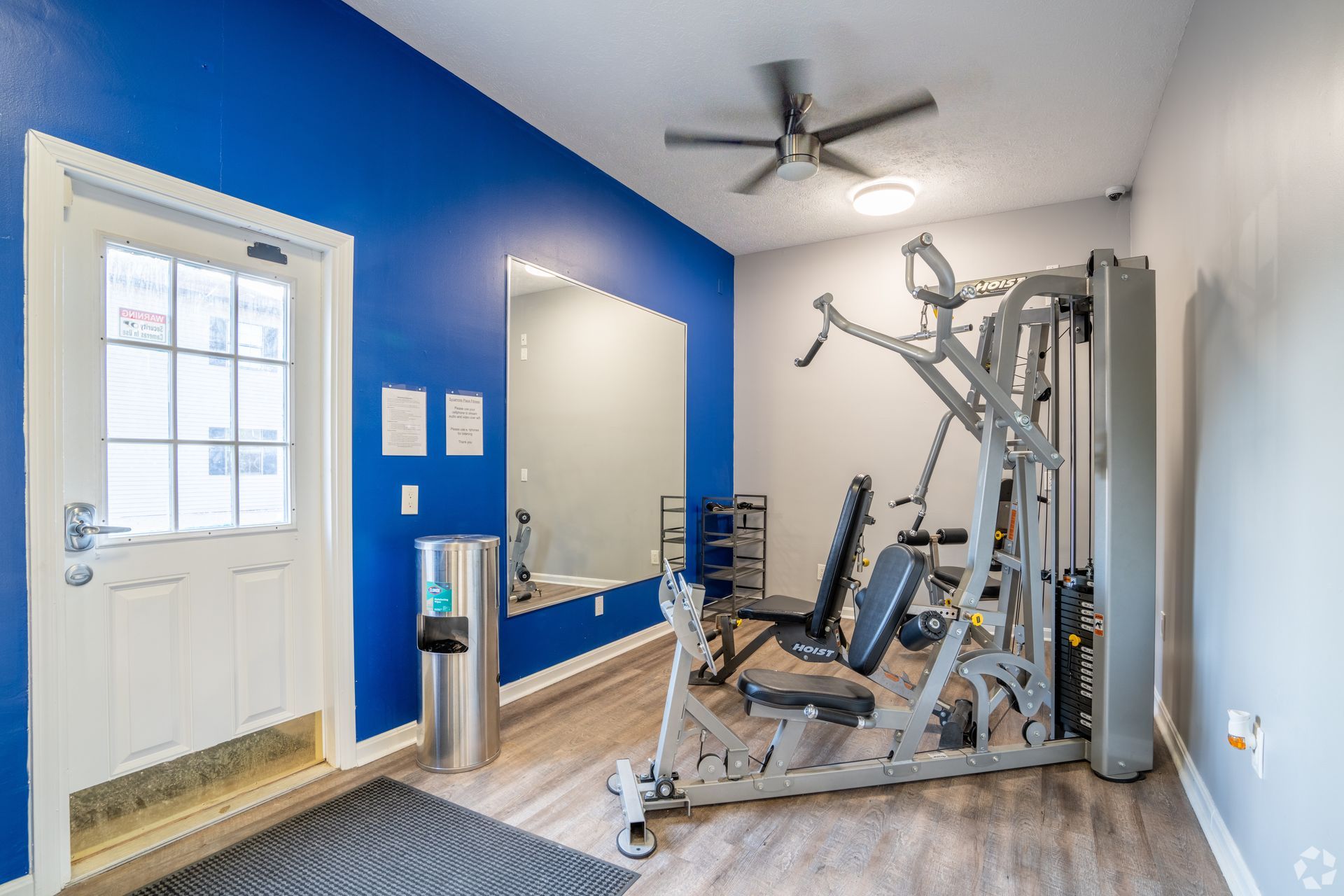 A gym with blue walls and a ceiling fan.