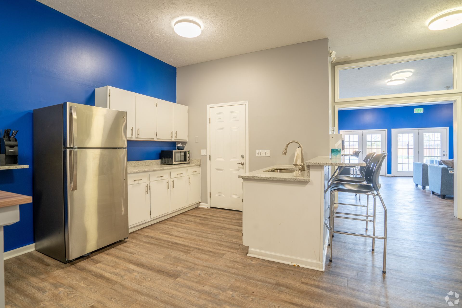 A kitchen with stainless steel appliances , white cabinets , a refrigerator and a sink.