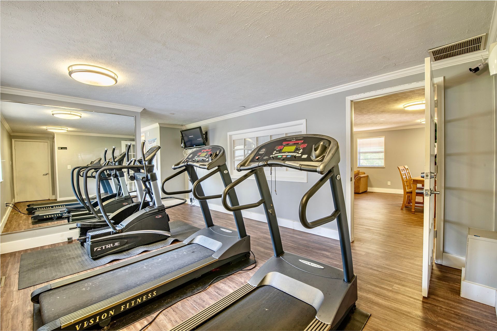 A gym with treadmills , ellipticals , and a large mirror.
