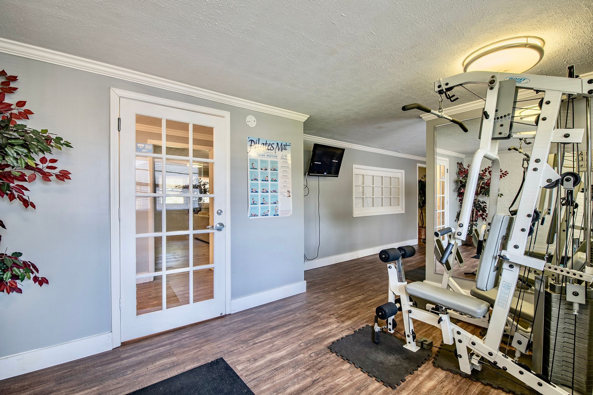 A gym with a lot of equipment and a tv on the wall.