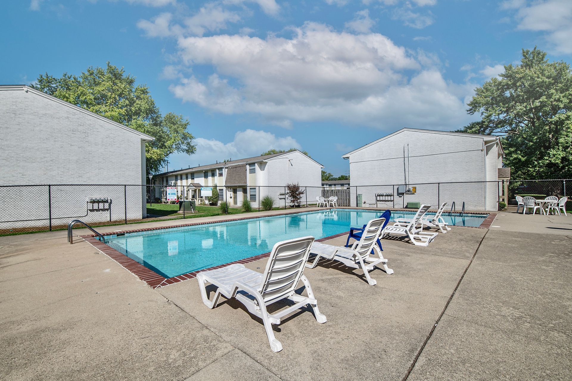 A swimming pool with chairs around it in front of a building.