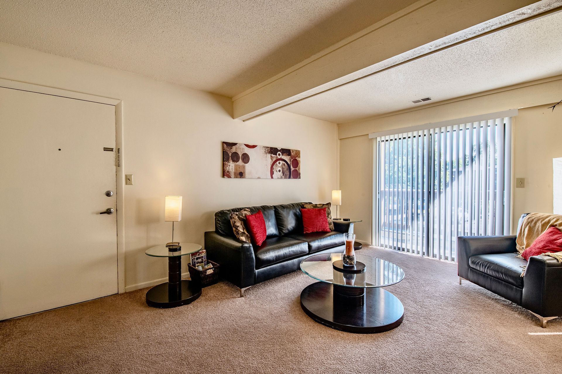 A living room with a couch , chair , coffee table and sliding glass doors.