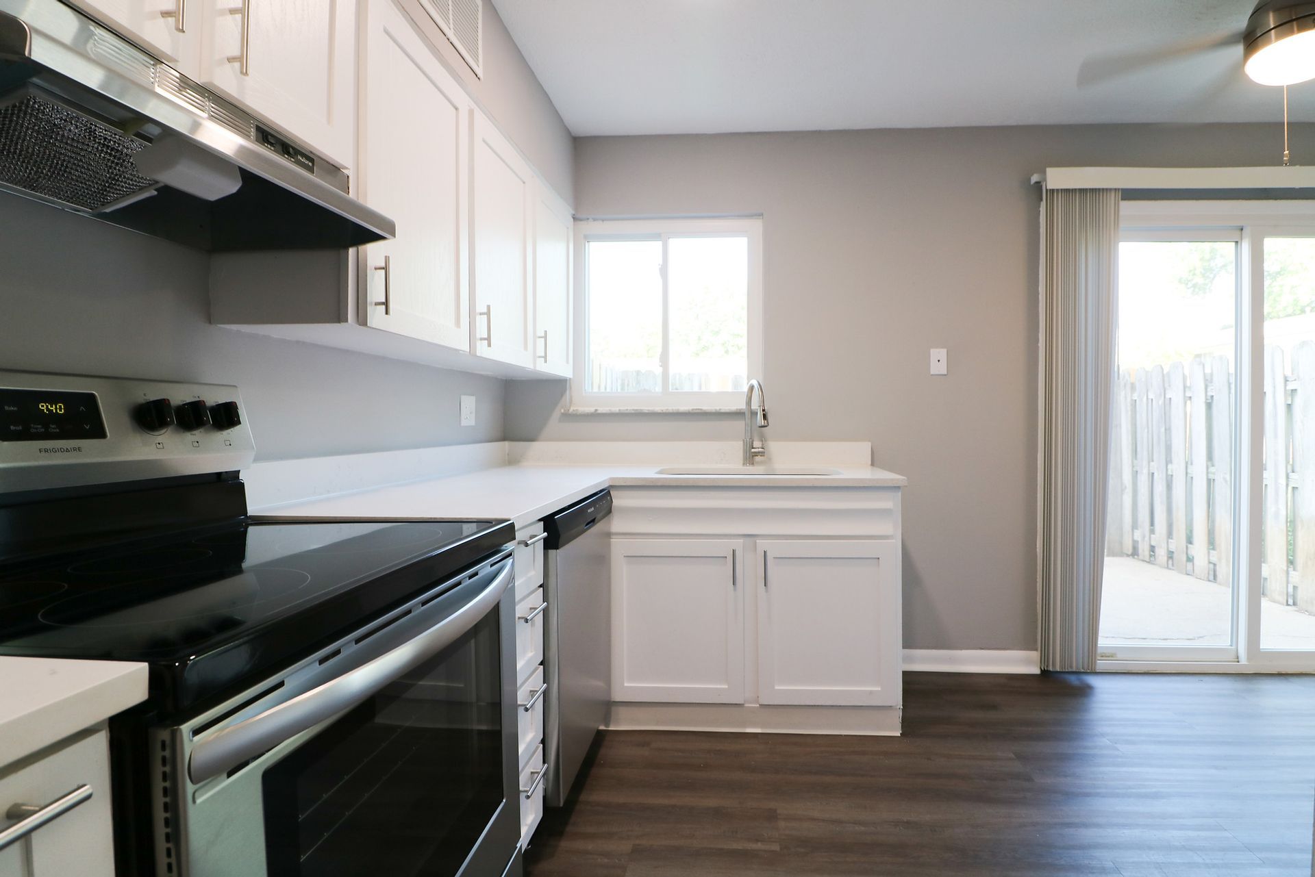 A kitchen with a stove , oven , sink and sliding glass door.