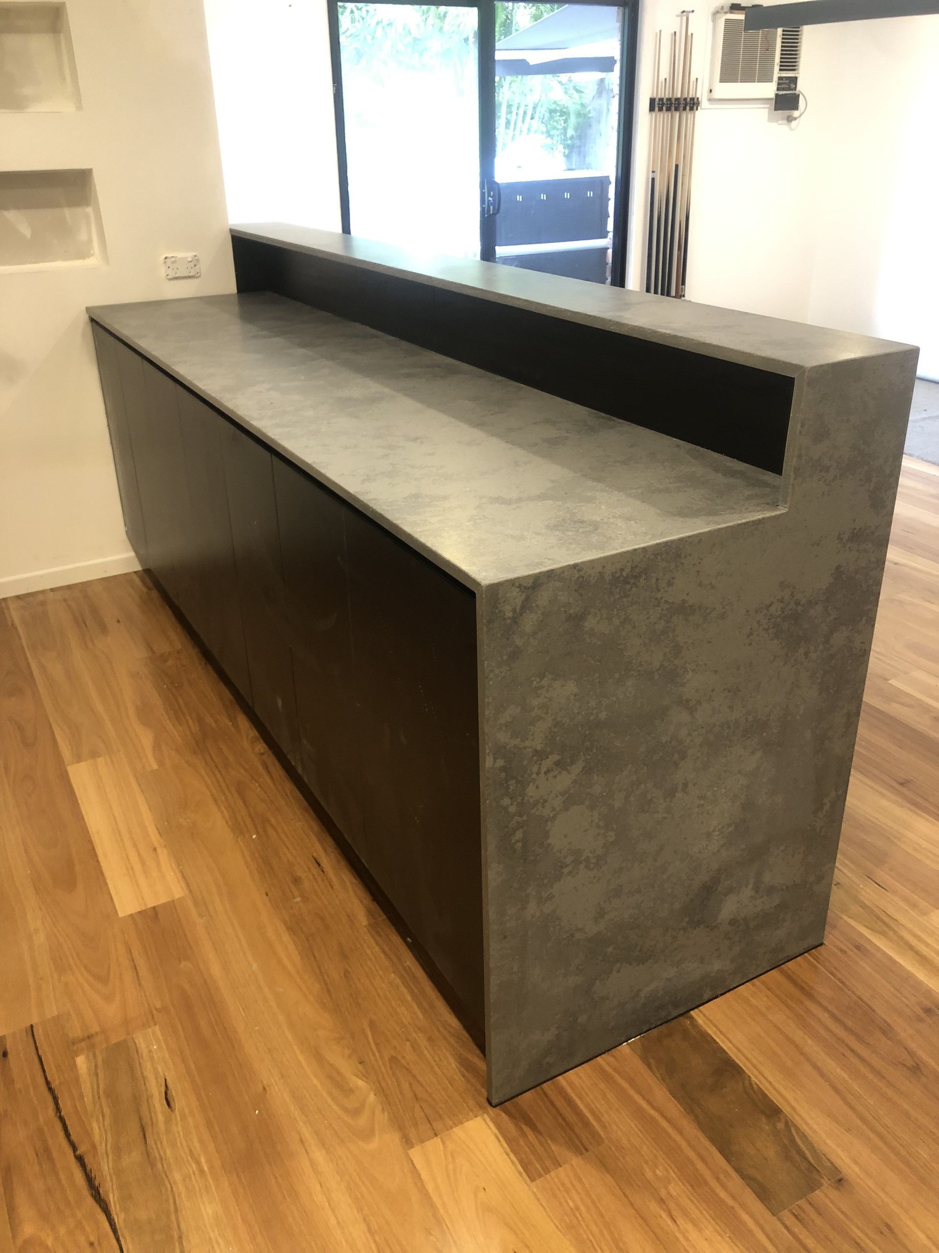 A Large black countertop is placed against a white wall— Universal Marble & Granite In Woolgoolga, NSW