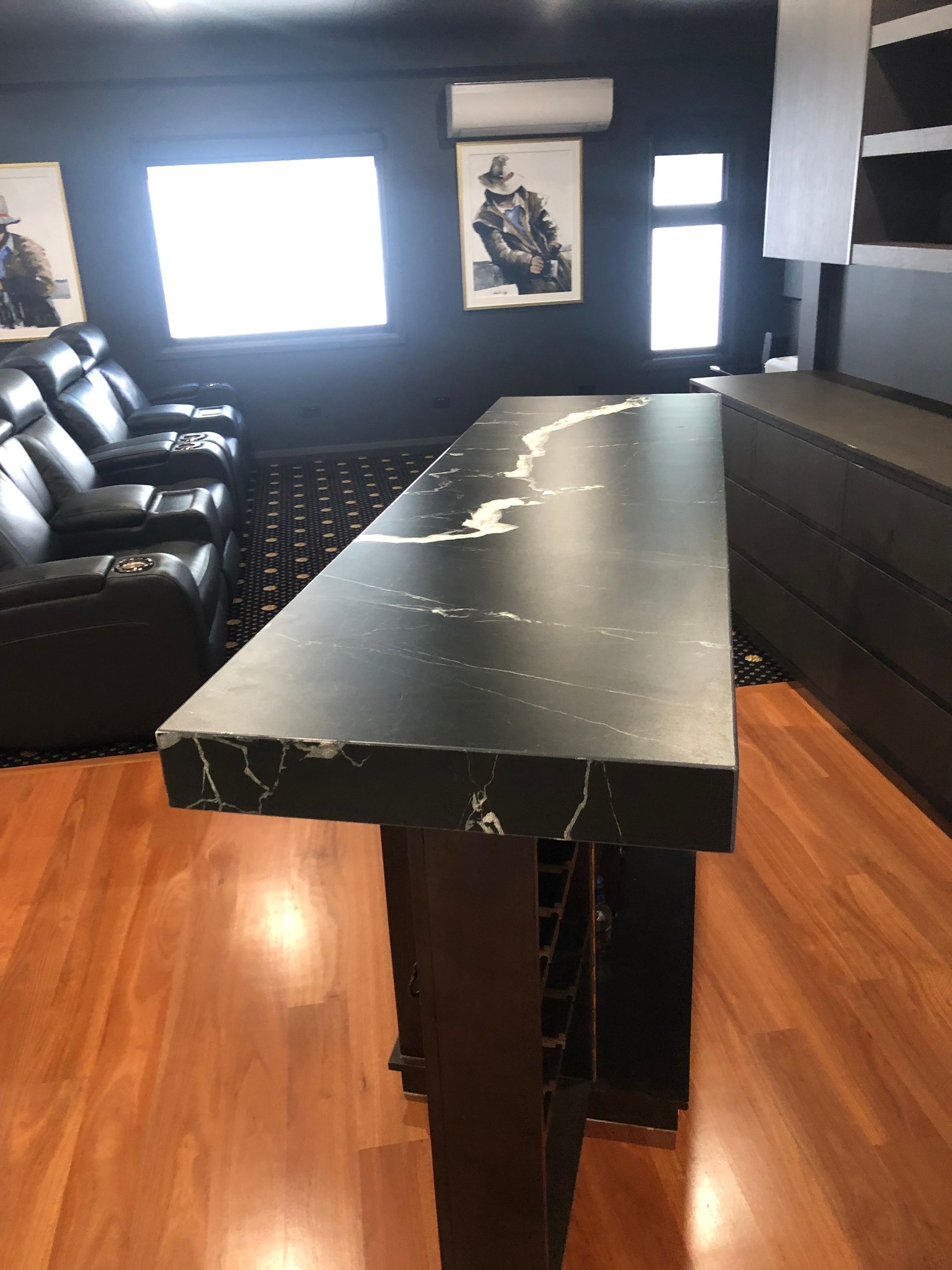 A large black table is in the middle of a room near commerical movie seats — Universal Marble & Granite In Woolgoolga, NSW