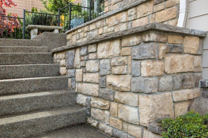 Stone wall and concrete steps leading to a building's entrance.