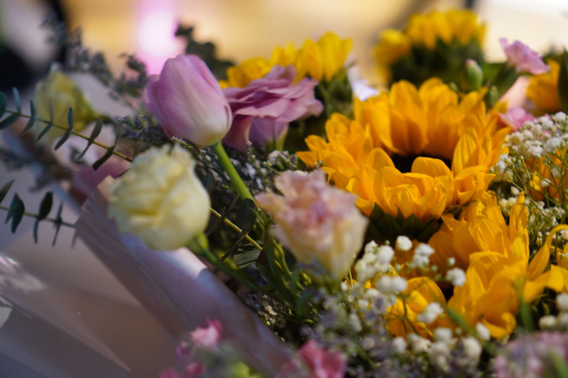 A close-up of a bouquet of flowers with sunflowers, roses, and baby's breath.
