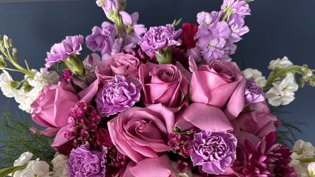 A person is arranging flowers in a vase on a table.