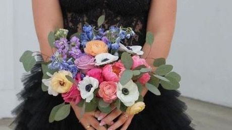 A table set for a wedding reception with plates, utensils, and a vase of flowers.