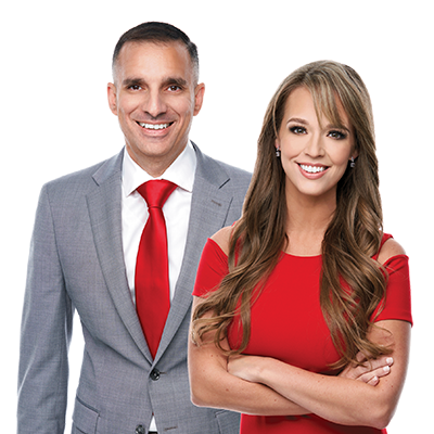 A man in a suit and tie stands next to a woman in a red dress