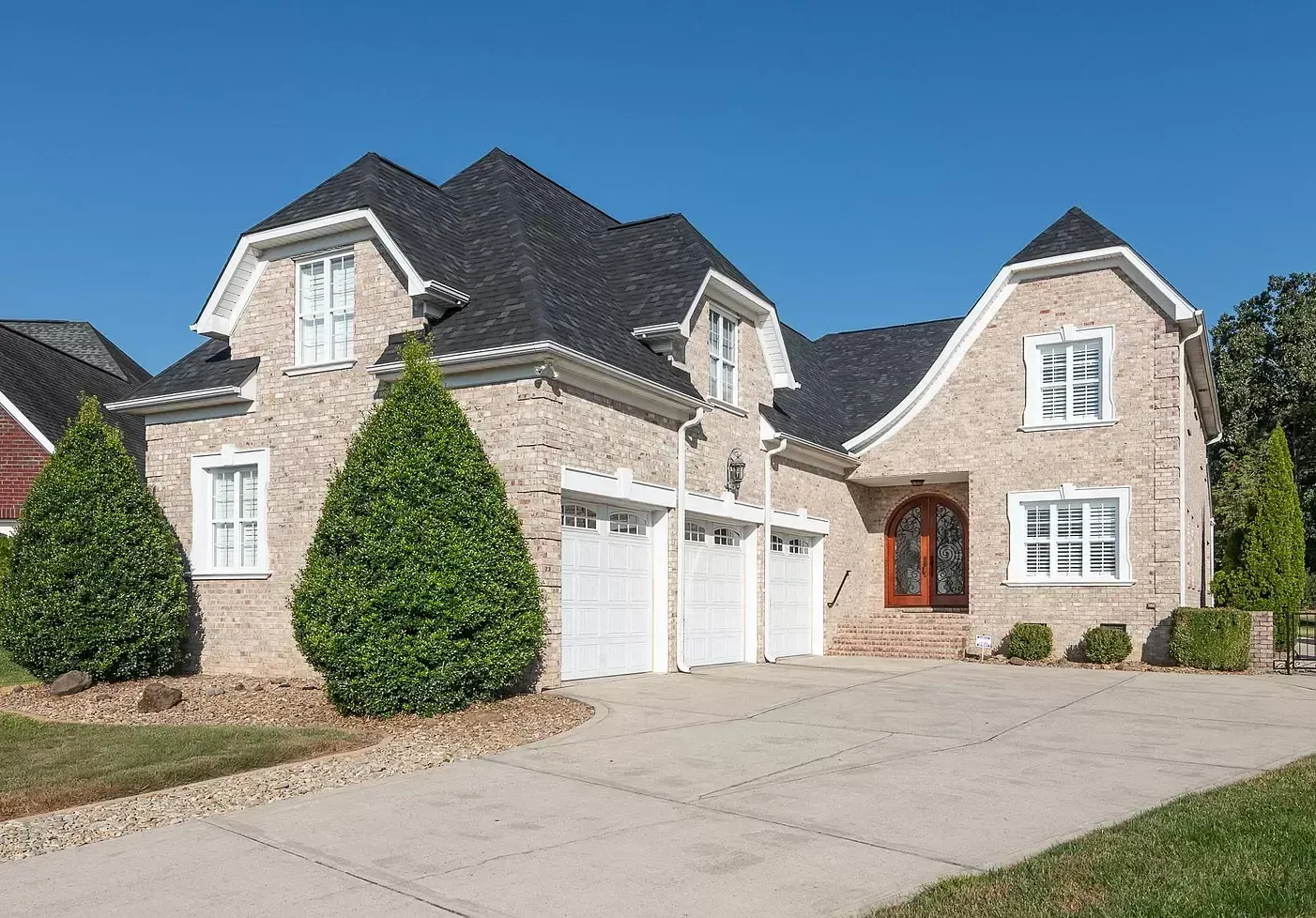 A large brick house with a black roof and white garage doors