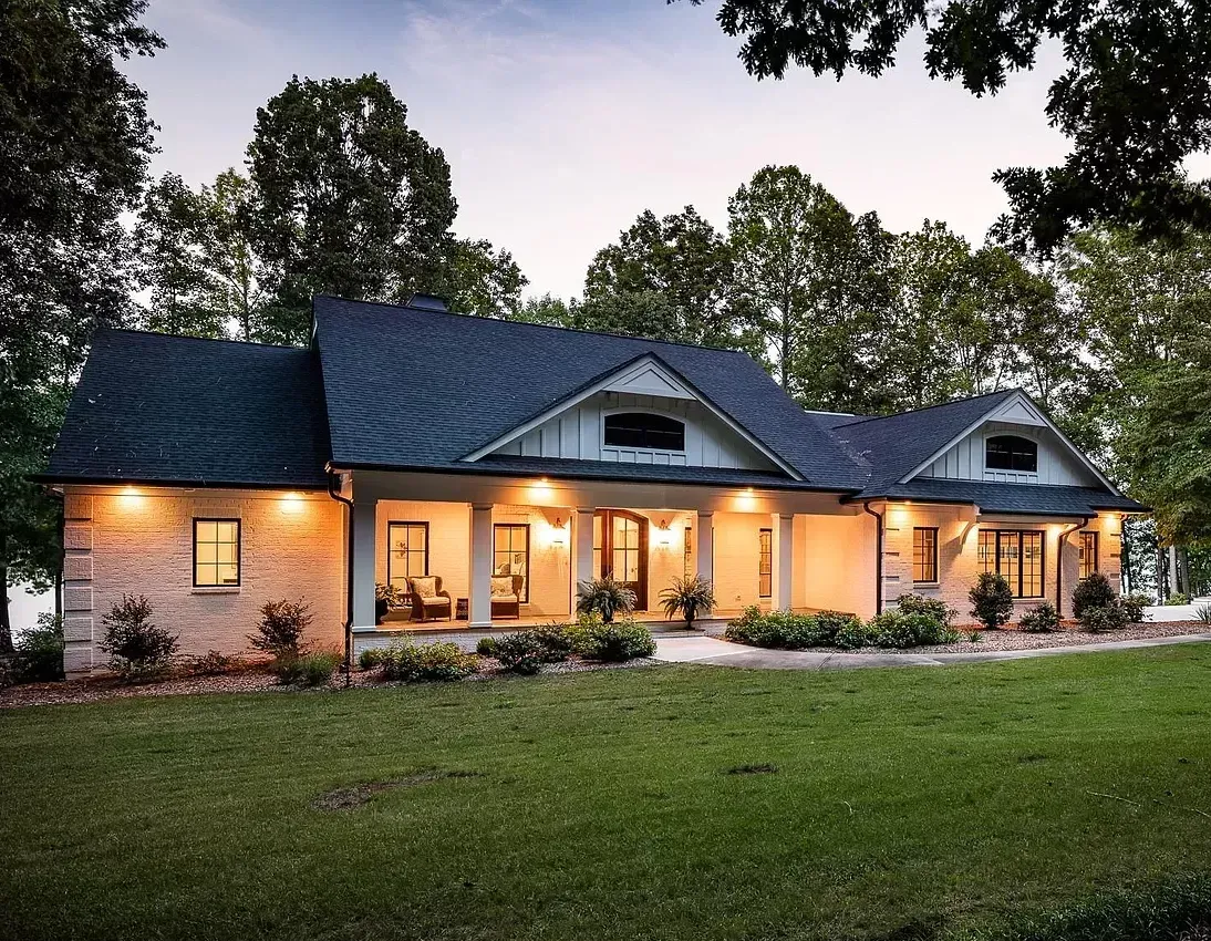 A large house with a blue roof sits in the middle of a lush green field