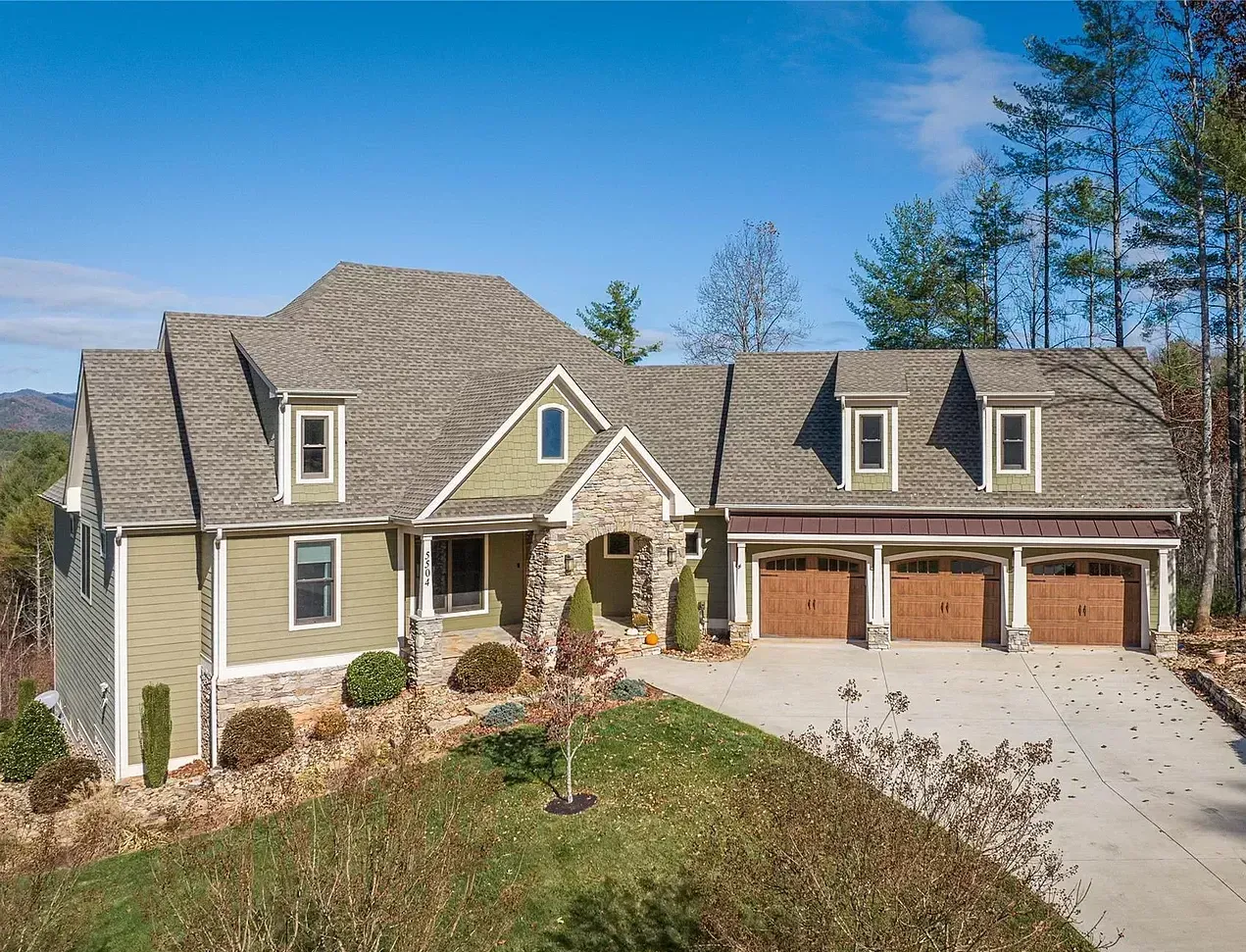 A large house with a gray roof and brown garage doors