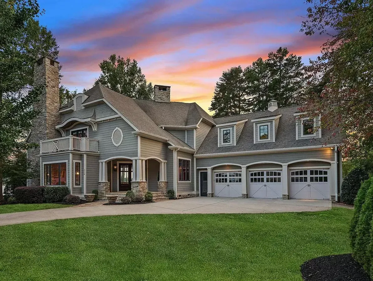 A large house with three garage doors and a sunset in the background