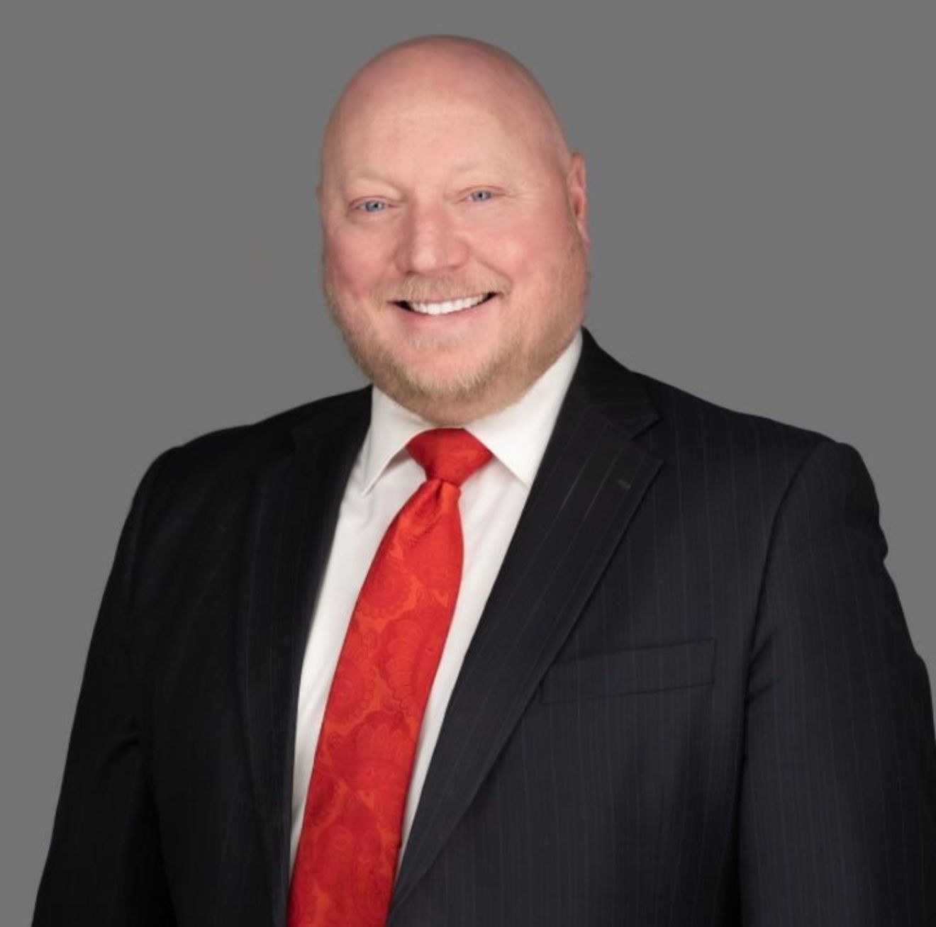 A man with glasses and a beard is smiling for the camera