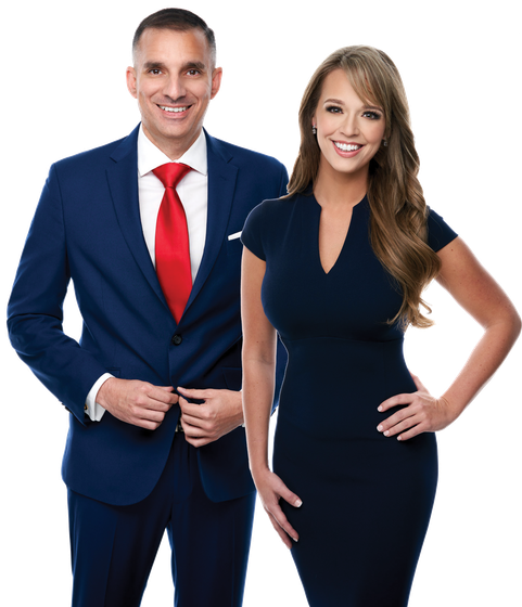 A man in a suit and tie stands next to a woman in a blue dress