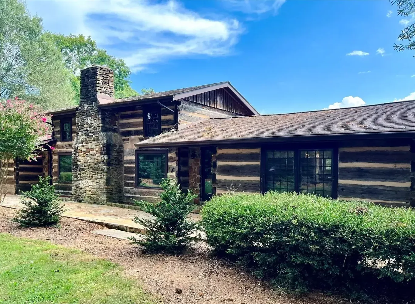 A log cabin with a stone chimney and a lot of windows