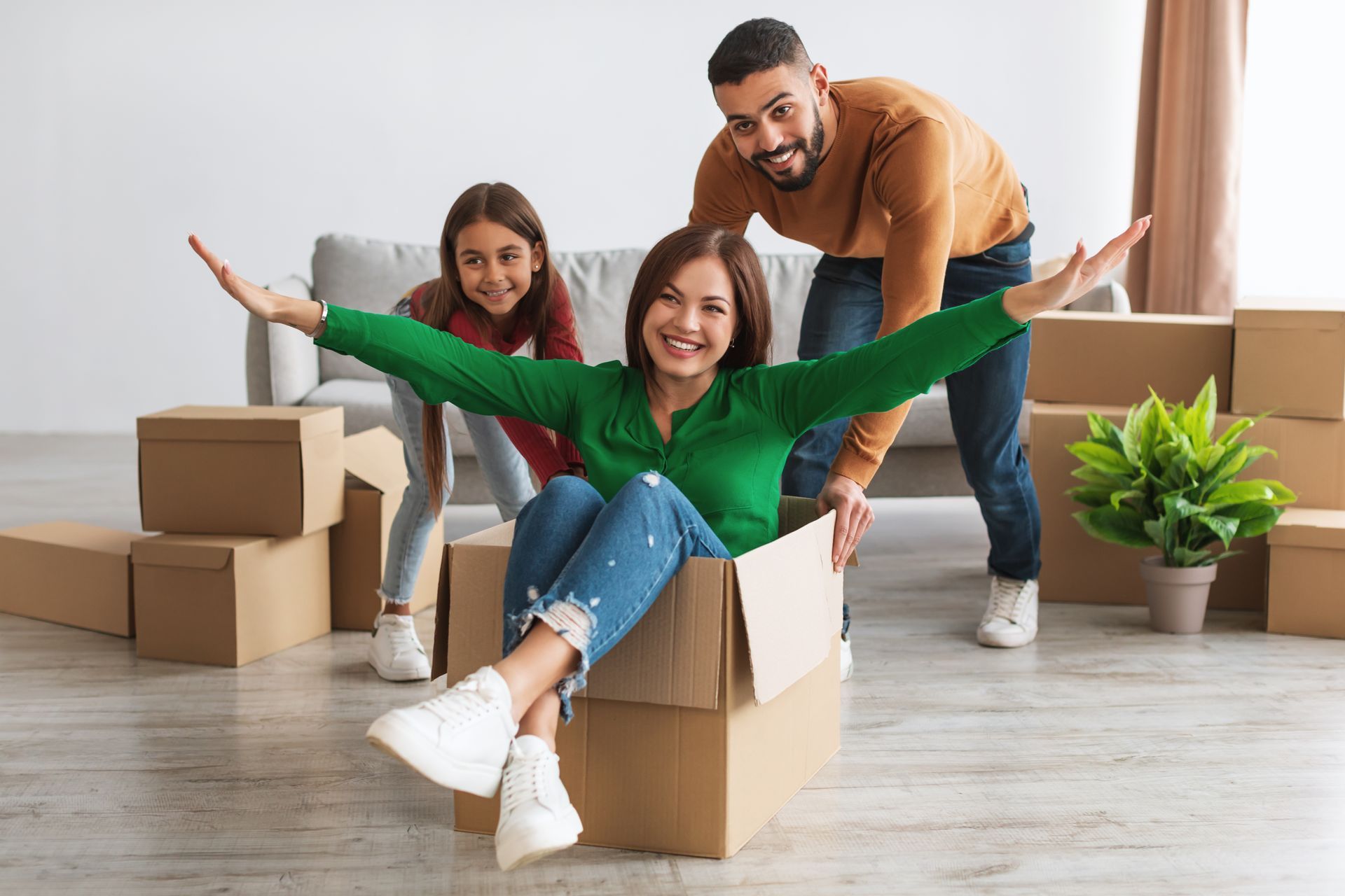 A family is playing with cardboard boxes in their new home.