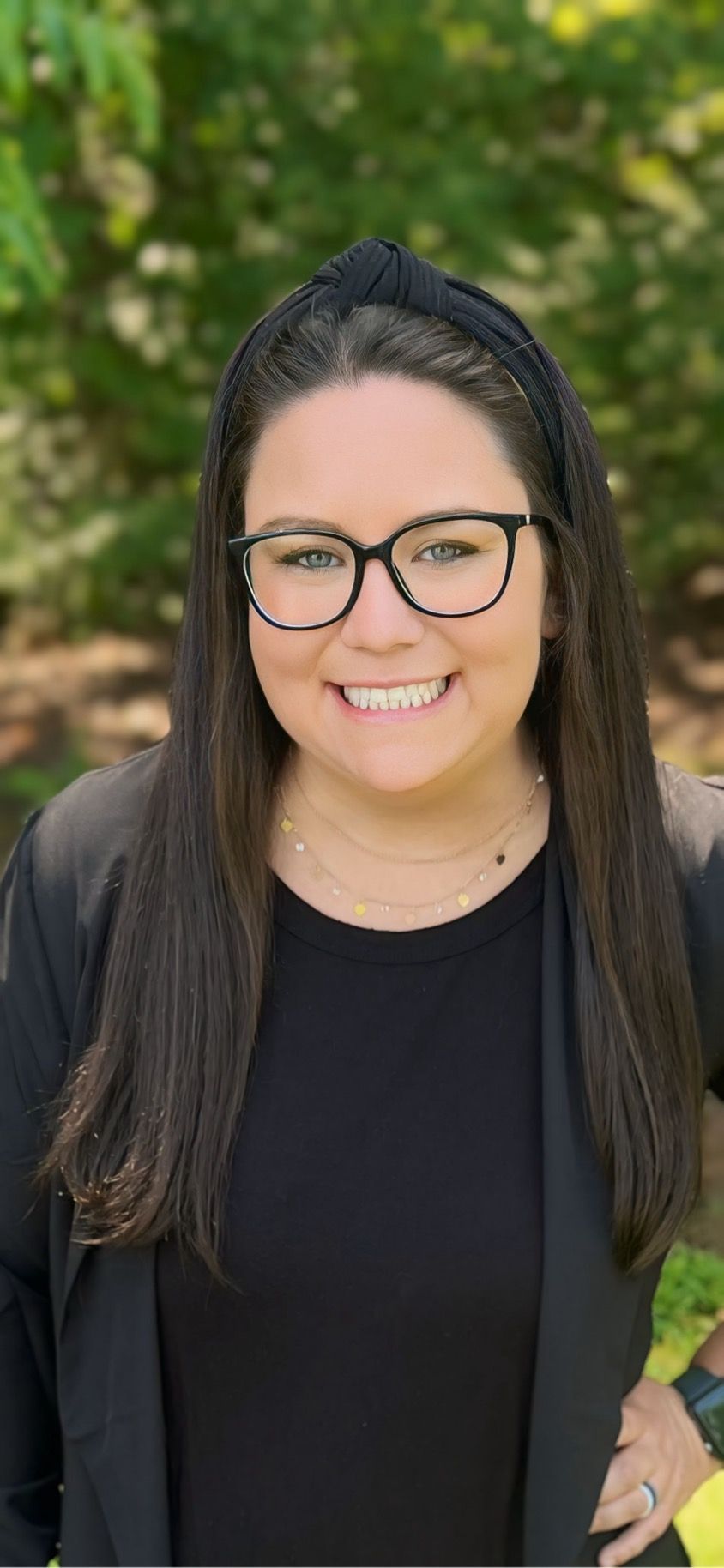 A woman wearing glasses and a headband is smiling for the camera.